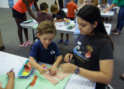 teen helping child with gluing activity