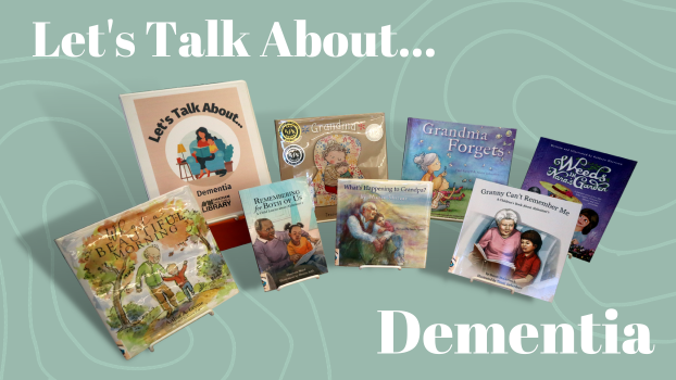 Seven children's picture books and a binder propped on easels. The binder is labeled "Let's Talk About... Dementia"