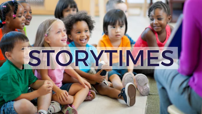 children sitting on the ground listening to librarian read book